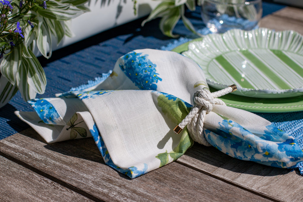 Decorative table setting with a folded fabric napkin, plates, and a plant on a wooden surface.